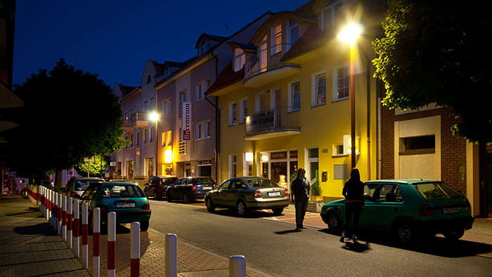 La gente camina de noche por las calles bajo alumbrado urbano de Philips
