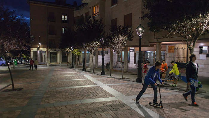 Niños jugando en una plaza por la noche bajo iluminación de Philips