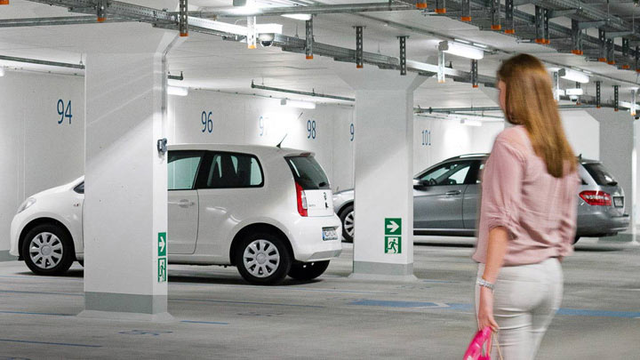 Una mujer se dirige a su coche en un aparcamiento público subterráneo bien iluminado 