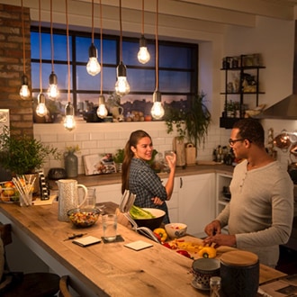 Pareja hablando bajo unas bombillas LED de Philips Vintage colgadas del techo que crean un brillo cálido y acogedor