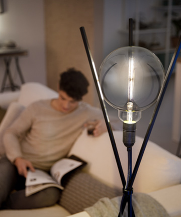 Hombre leyendo junto a una bombilla LED con el diseño de Philips Modern 