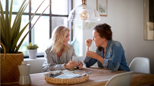 Dos mujeres en casa hablando bajo una bombilla de Philips