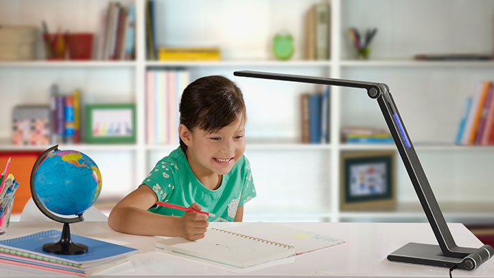 Niña haciendo los deberes con una lámpara de escritorio de LED de Philips