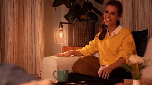 Mujer disfrutando de la luz regulada en el sofá de su hogar