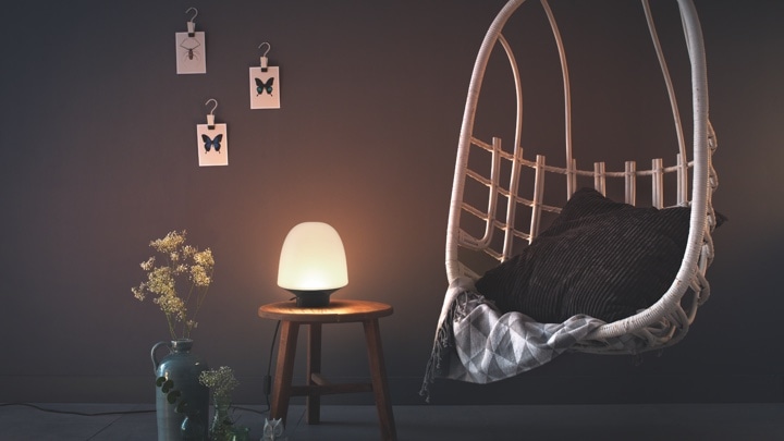 Dormitorio iluminado con una lámpara para el dormitorio colocada sobre una mesa. Lámpara de dormitorio de pie o de mesilla