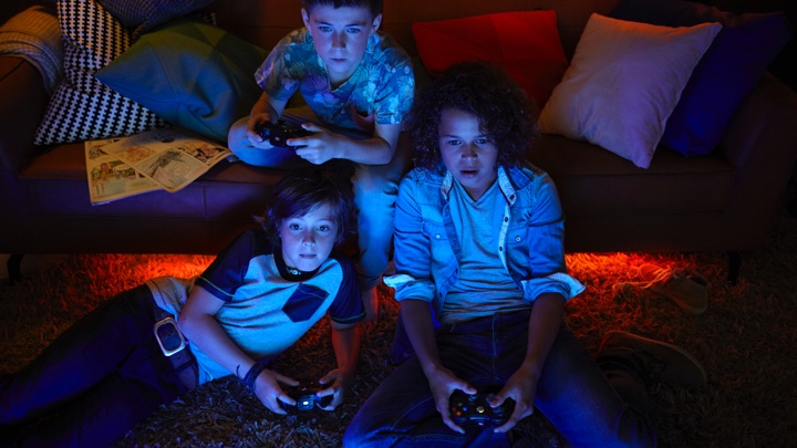 Tres chicos jugando a videojuegos con iluminación ambiental