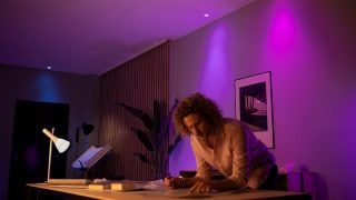 Philips HUE luces LED inteligentes crean un ambiente vibrante de color púrpura y rosa en la sala de estar, mostrando iluminación de humor personalizable para noches de cine y relajación en hogares modernos.