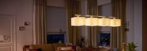 La moderna luz colgante LED con múltiples tonos de tela ilumina una acogedora sala de estar, mostrando soluciones de iluminación de hogar elegantes y energéticamente eficientes para la comodidad ambiental de la noche.