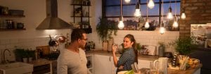 "Cocina moderna con luces colgantes LED de estilo vintage que iluminan a dos mujeres que disfrutan de la cena, creando un ambiente cálido y acogedor."