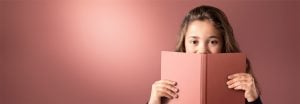 "Niña mirando un libro rosa sobre un fondo suave iluminado por LED, mostrando una iluminación cálida y uniforme para entornos de lectura cómodos".