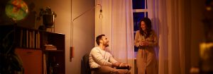 "Lámpara de pie con bombilla LED de estilo vintage que crea un ambiente cálido para la conversación nocturna en pareja, mostrando una iluminación ambiental energéticamente eficiente en una acogedora sala de estar".