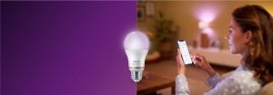 "Mujer que controla la iluminación LED a través de la aplicación para teléfonos inteligentes, creando un ambiente cálido en una acogedora sala de estar con tecnología conectada para el Inicio".