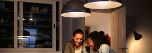 "Las modernas luces colgantes LED crean una atmósfera cálida para dos mujeres que disfrutan de una conversación, mostrando soluciones de iluminación de Inicio energéticamente eficientes".