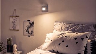 Elegante dormitorio con foco de LED ajustable que crea un ambiente acogedor, iluminando la ropa de cama geométrica y decoración minimalista.